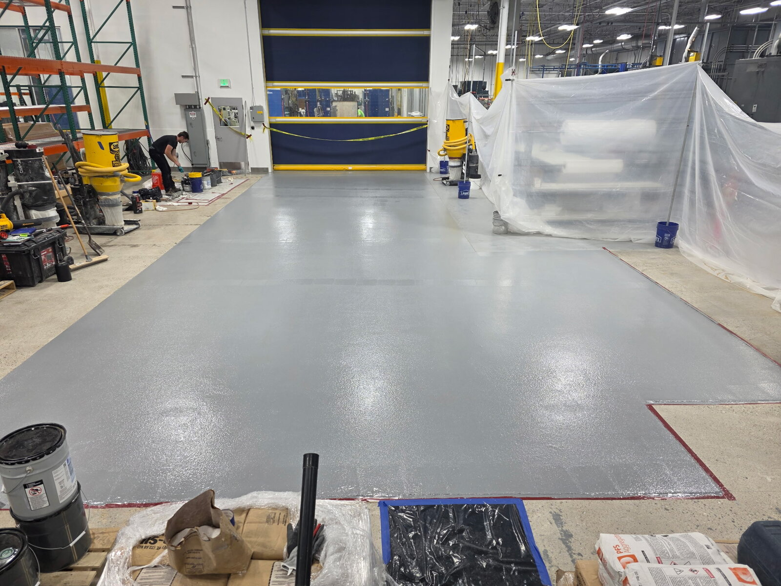 Gray epoxy topcoat mid-application in a manufacturing facility
